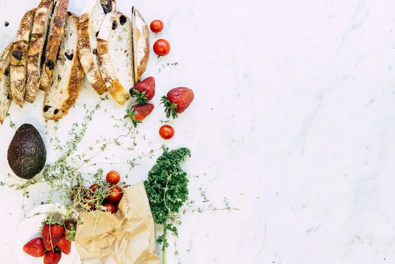 Libro de cocina saludable abierto junto a verduras frescas y utensilios en una encimera