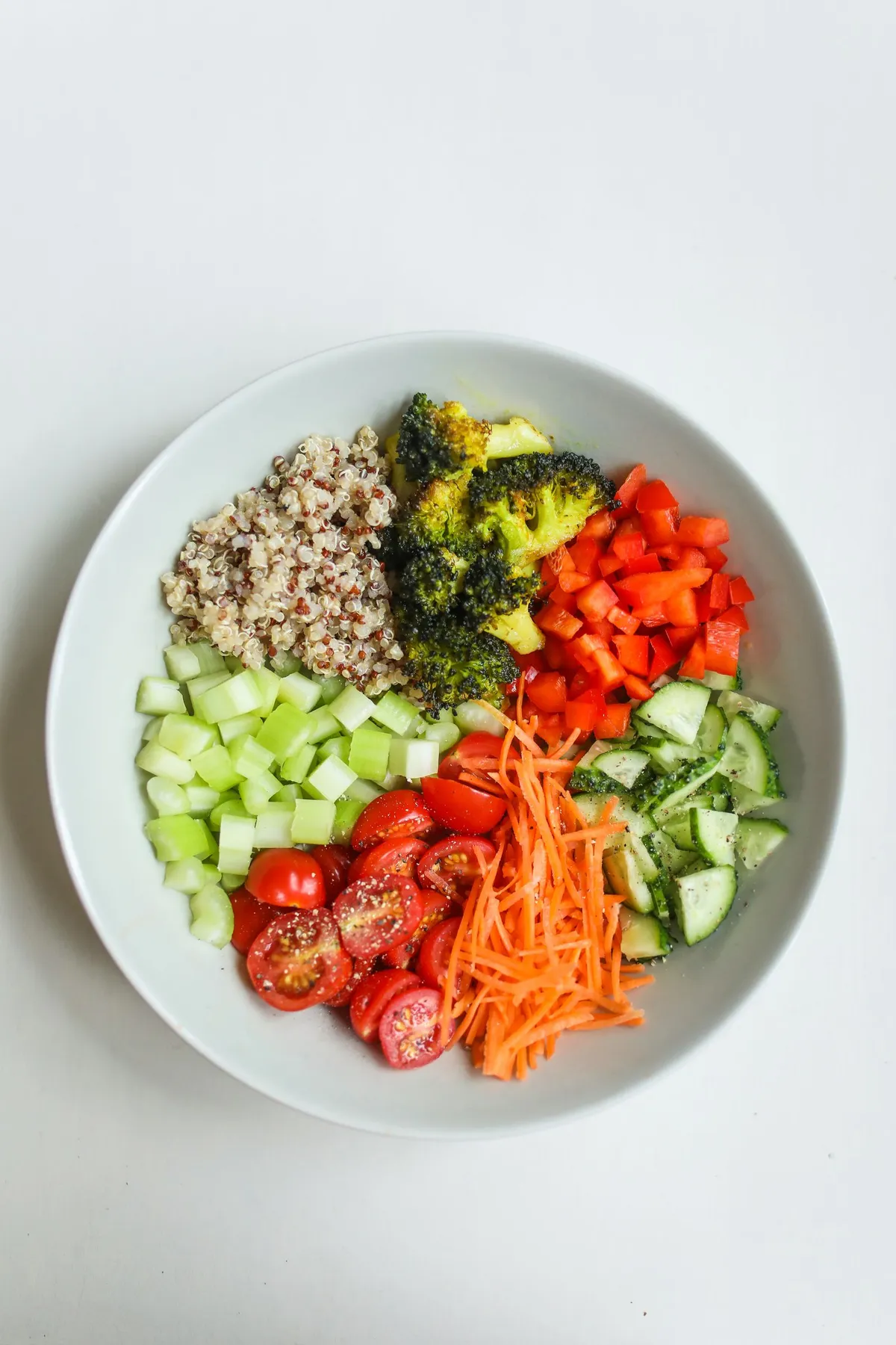 Mujer madura sonriente preparando una ensalada de verduras frescas en la cocina, ejemplo de dieta antiinflamatoria en la menopausia