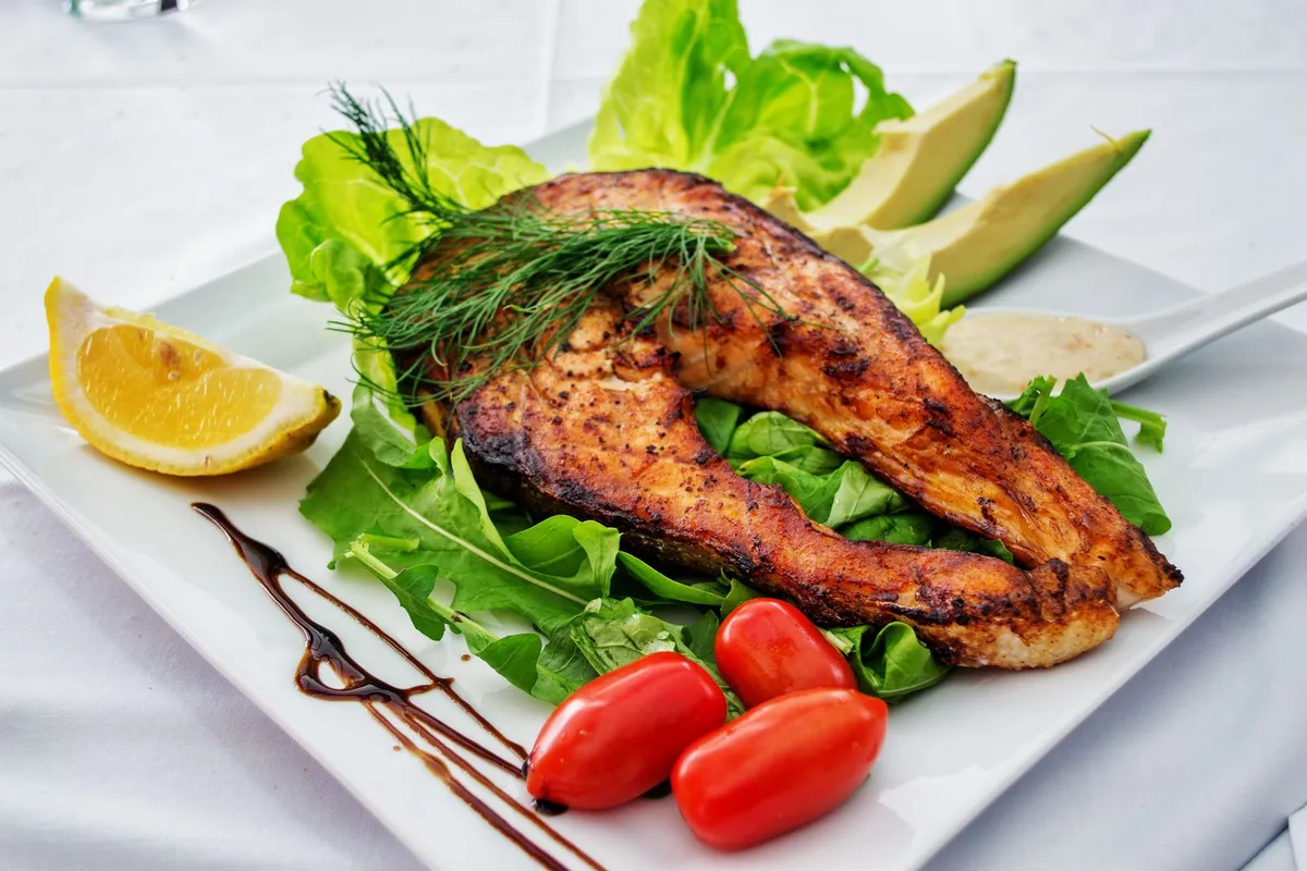 Plato de salmón a la plancha con aguacate y verduras verdes, ejemplo de comida keto de calidad