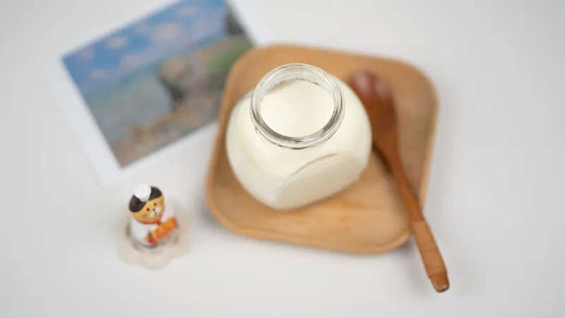 Tarro de cristal con yogur natural sin azúcar y cuchara de madera sobre un plato